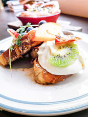 Delicious sweets French toasts with vanilla yogurt, blueberries jam and fresh fruits for a vitamin breakfast.