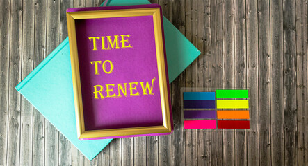 Frame with the inscription Time to renew  and bright notepads and stickers on a wooden table,...