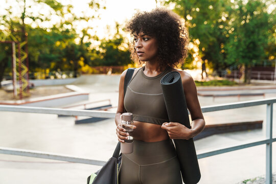 Image of african american sportswoman standing with water bottle