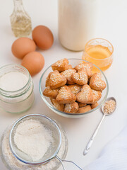 shortbread cookies with sesame seeds in a heart shape, and ingredients for cooking over white background
