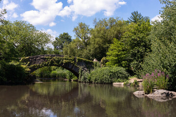 Fototapeta na wymiar Gapstow Bridge over the Pond at Central Park with Green Plants and Trees during Summer in New York City