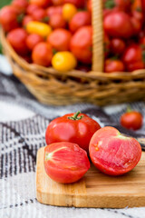 A cut tomatoes on a plank. Harvesting by autumn. Against the background of a large basket of tomatoes.