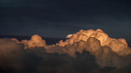 Full moon hiding behind clouds at night