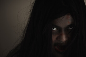 Girl zombie in blood. Closeup face and eyes of Asian Woman ghost with blood. Horror creepy scary...