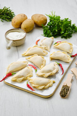 Potato vareniki on marble serving board with ingredients