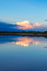 Beautiful sunset by the lake. Bright clouds are reflected in the water. Kyrgyzstan.