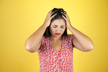 Young beautiful woman over isolated yellow background suffering from headache desperate and...