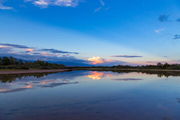 Beautiful sunset by the lake. Bright clouds are reflected in the water. Kyrgyzstan.