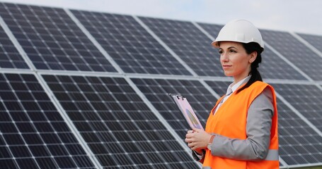 Portrait of female engineer on background field of photovoltaic solar panels. Woman technician at...