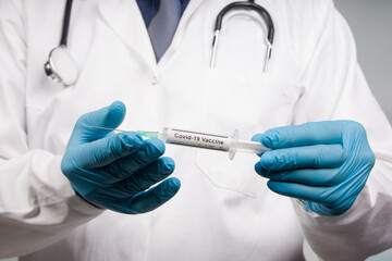 Close up of doctor's hands in medical gloves with a syringe with Covid-19 serum/vaccine