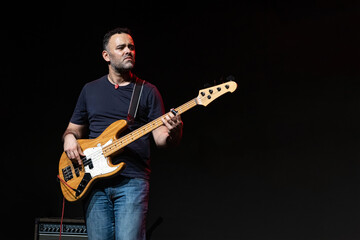 Obraz premium Caucasian Man is Performing on the Stage. Handsome Male Person is Playing on Bass Guitar at Concert.