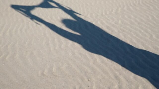 Close up of young woman taking off her bra at nude beach. Concept of sunbathing naked on the sandy ocean beach. Naturalist lifestyle.