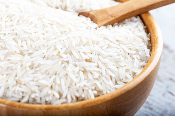 Wooden bowl full of basmati rice on wooden background.