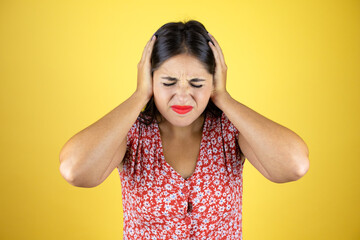 Young beautiful woman over isolated yellow background covering ears with hands with annoyed expression for the noise of loud music. Deaf concept.