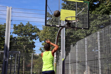 Junger Mann spielt Street Basketball im Park 