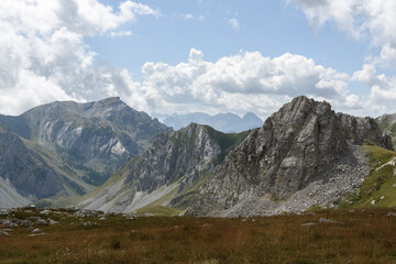 Fototapeta premium landscape of the mountain peaks of the Alps, rugged and rocky mountains, part of the French Alps mountain range. The sky between clear blue, is covered with white clouds, you can see in the valley the