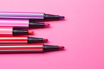 five open markers or pens of pink, purple, pink color lie like steps on a pink background, isolated mock up.