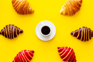 Set of coffee with croissants - chocolate, berry, classic - on yellow table