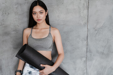 Image of beautiful asian girl in sportswear posing with yoga mat