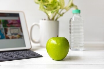 Healthy snack with working in the office.  Green apple and fresh water for diet Health Plan with laptop on white dress working.  