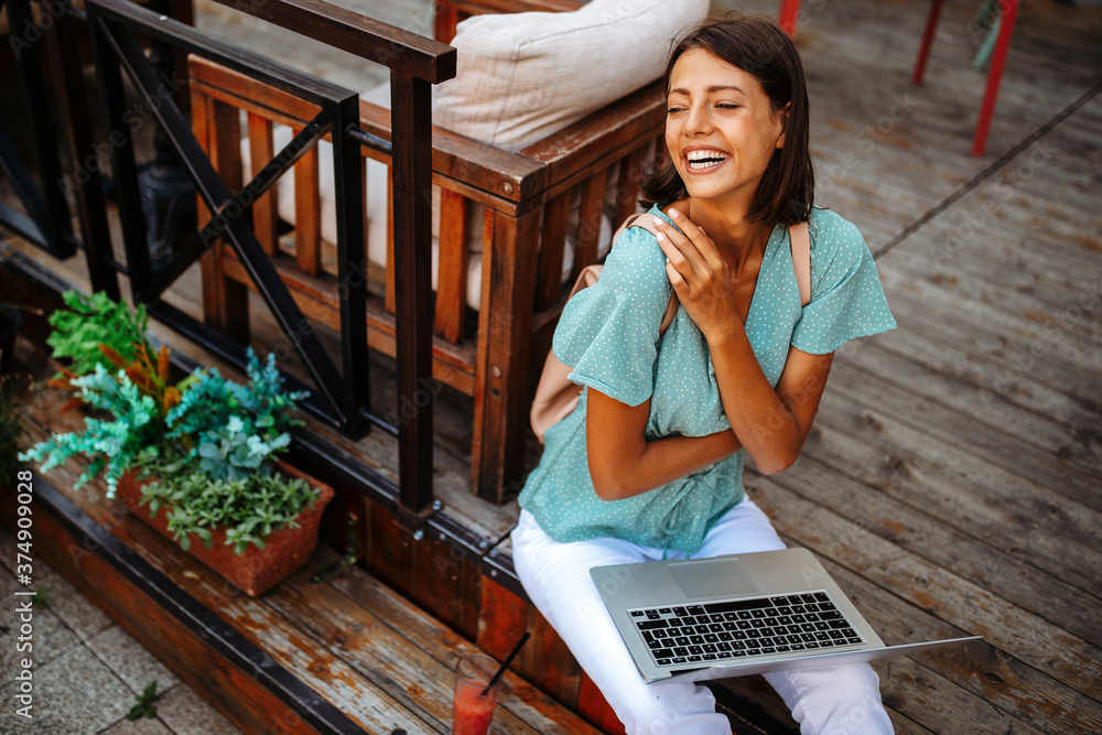 Wall mural Beautiful woman with laptop outdoor. People, technology, work, fun, study concept