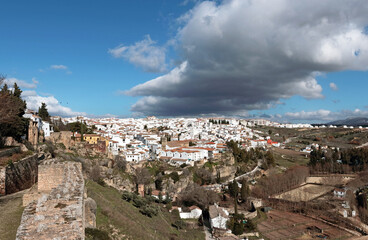 Fototapeta na wymiar Ronda, Andalusia, Spain: a dark cloud hovers over the old town on a sunny winter day