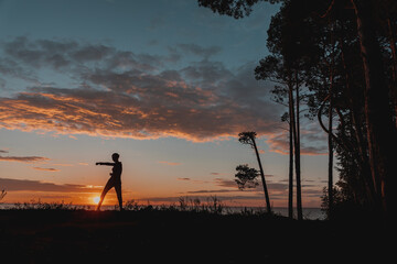 the girl is engaged in karate on the background of the setting sun
