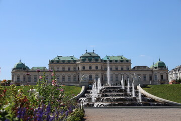 Fototapeta premium Schloss Belvedere vor einem künstlichen Wasserbrunnen und wunderschönen Blumen im Sommer
