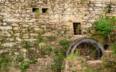 Parede de pedras medieval rústica com janela com grades de ferro e grama com musgo nascendo