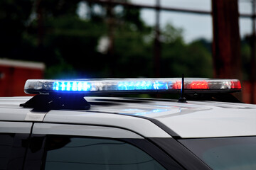Close up of police lights flashing on top of a police car in day time.  Police car at the scene of a crime or accident with red and blue lights and siren. 