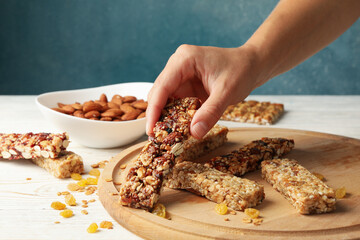 Female hand hold granola bar on wooden background with granola bars