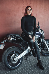 Fototapeta na wymiar Redhead sexual female rider sitting on modern bike