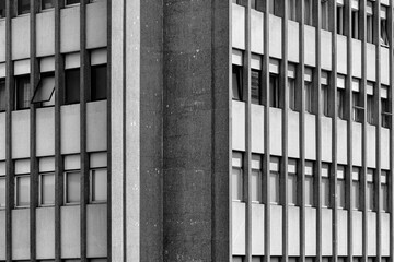 Detalhes de fachada geométrica de prédio com colunas verticais em concreto.