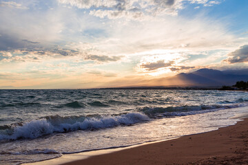 Fototapeta na wymiar Beautiful sunset by the lake. Bright clouds are reflected in the water. Kyrgyzstan.