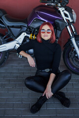 Fototapeta na wymiar Cute redhead woman sitting and posing with her motorcycle