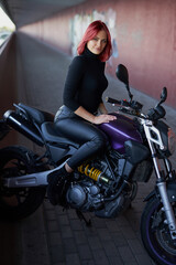 Redhead sexy female biker rides her modern motorcycle