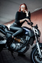 Fototapeta na wymiar A modern motorbike and female biker with red hairs