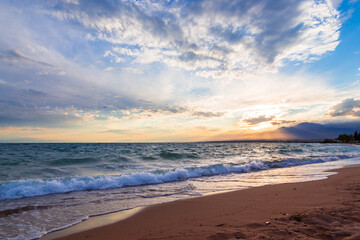 Beautiful sunset by the lake. Bright clouds are reflected in the water. Kyrgyzstan.