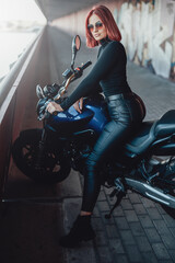 Obraz na płótnie Canvas A modern motorbike and female biker with red hairs