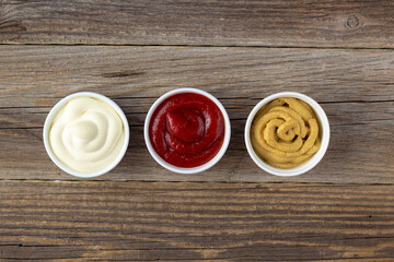 Set of three kinds of classic sauces on wooden background. Mayonnaise ketchup mustard