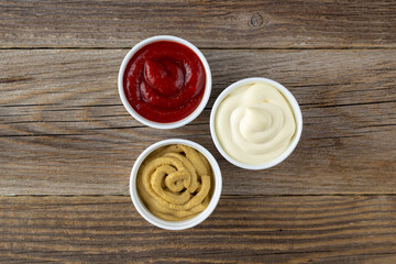 Set of three kinds of classic sauces on wooden background. Mayonnaise ketchup mustard