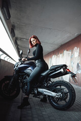 Fototapeta na wymiar An attractive girl with red hairs sitting on her urban bike