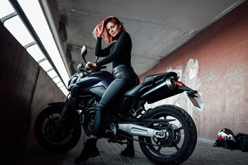 Plakat An attractive girl with red hairs sitting on her urban bike