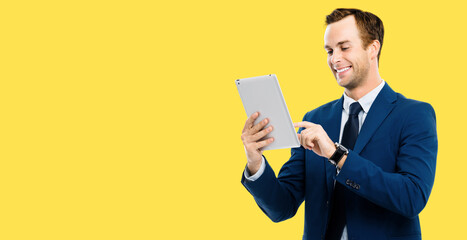 Portrait image - happy smiling businessman using no-name tablet pc, over yellow color background. Success in business concept studio picture. Copy space for some text.