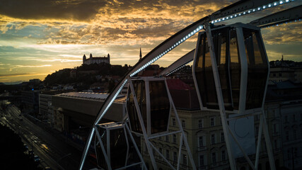 Bratislava ferris wheel detail at sunset with castle and yellow clouds in background drone photo