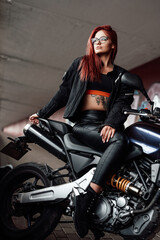 A modern motorbike and female biker with red hairs