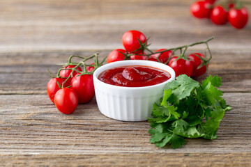 White bowl of tomato sauce with parsley and tomato. Ketchup on natural wooden background