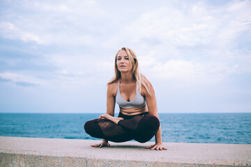 Fototapeta na wymiar Focused woman practicing yoga near sea
