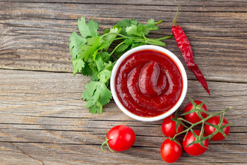 White bowl of tomato sauce with parsley pepper and tomato. Ketchup on natural wooden background