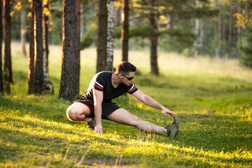 A young handsome man trains in nature